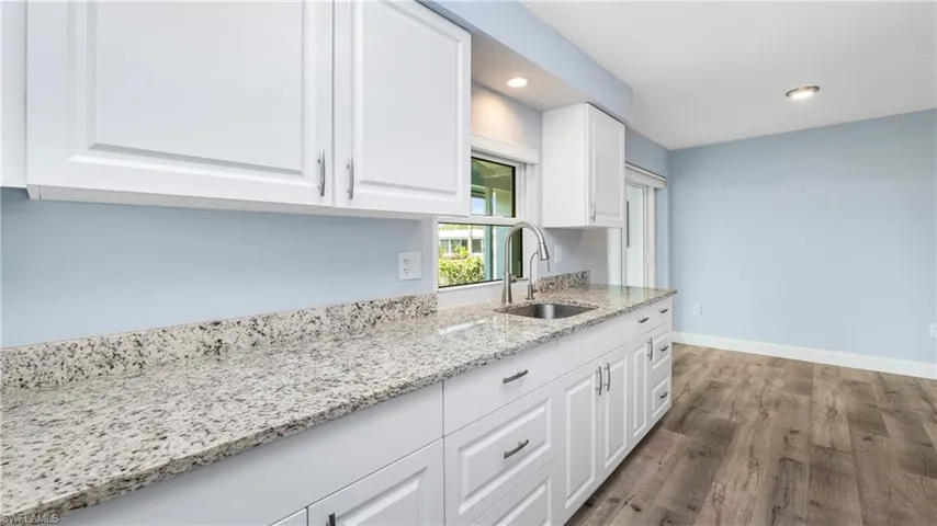 Kitchen with white cabinets, light stone countertops, recessed lighting, and wood finished floors