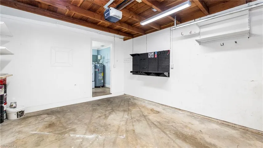 Garage featuring wood ceiling, electric water heater, and a garage door opener