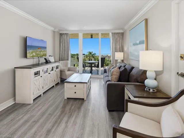 Spacious living area featuring wood-finish flooring, crown molding, and a built-in media console