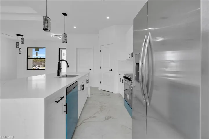 Modern kitchen featuring a waterfall island with a stainless steel sink and matte black faucet, stainless steel appliances, marble-finish flooring, and pendant lighting with geometric accents