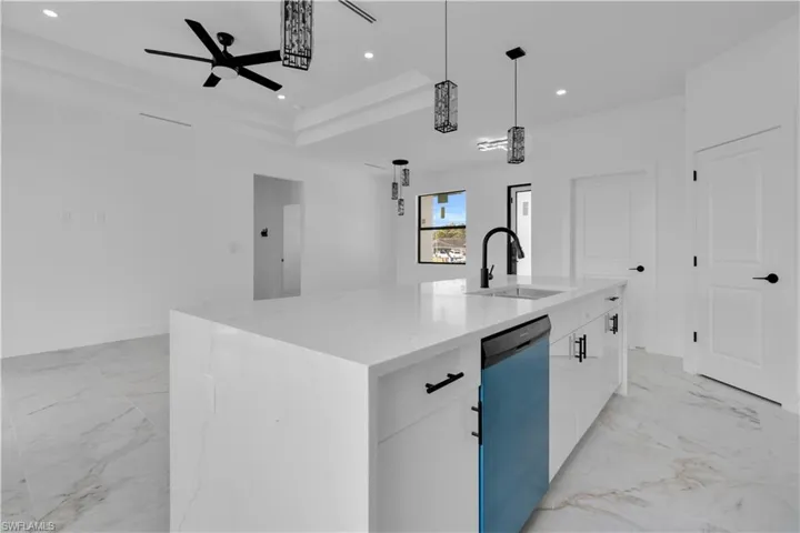 Kitchen island featuring a waterfall-edge countertop with an undermount sink and matte black faucet