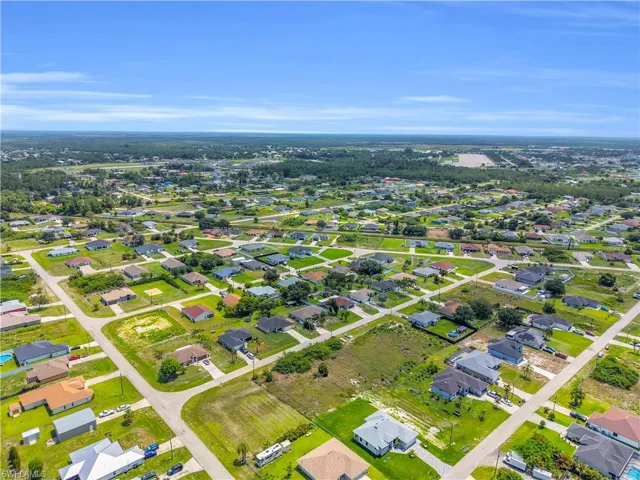 Expansive aerial perspective showcasing a residential neighborhood with numerous single-story homes, many featuring green lawns and varying rooflines