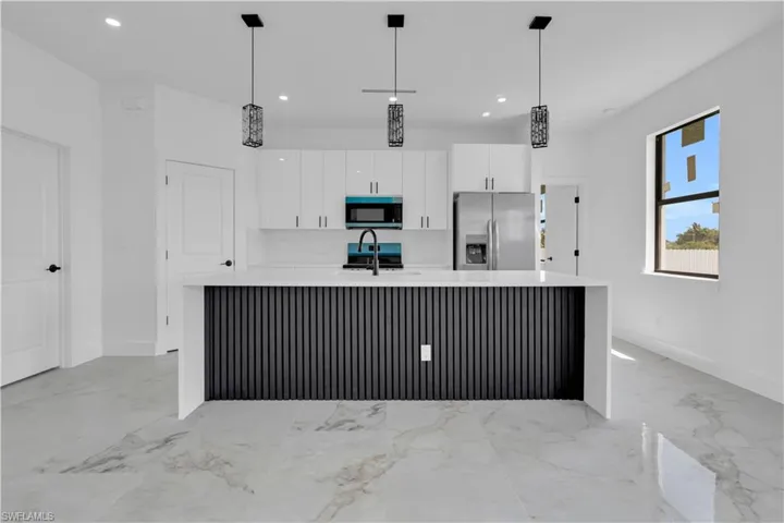 Open concept kitchen featuring an island with a slatted base, white countertops, stainless steel appliances, and ceiling-mounted pendant lighting
