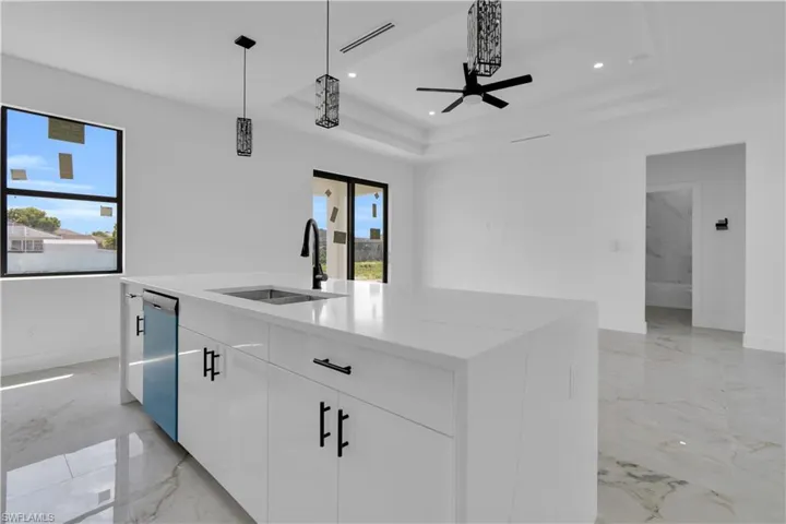 Kitchen island featuring a white countertop with an undermount sink and matte black faucet