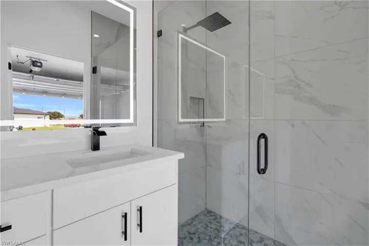 Contemporary bathroom featuring a spacious walk-in shower with clear glass enclosure and rainfall showerhead, alongside a vanity with an integrated sink and matte black fixtures