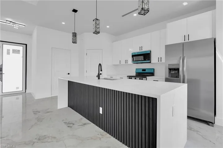 Kitchen featuring a spacious island with a slatted base, white countertops, and a black faucet