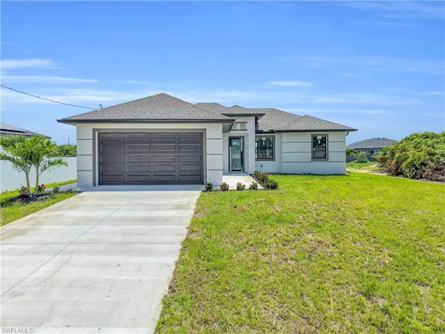 Contemporary single-story residence featuring a two-car garage, a concrete driveway, and a tiled roof