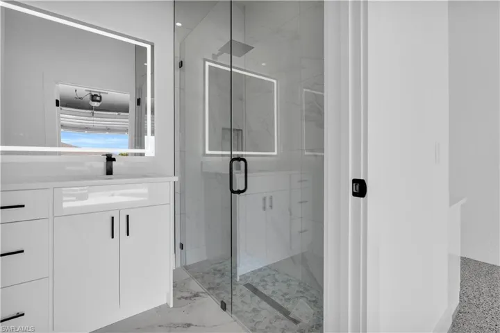 Contemporary bathroom featuring a frameless glass shower enclosure, a rainfall showerhead, and a vanity with a white countertop