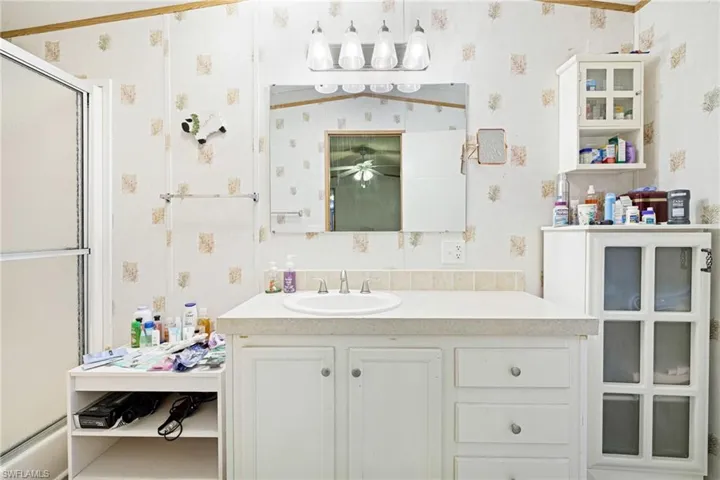 Full bath featuring wallpapered walls, a shower with shower door, vanity, and ceiling fan