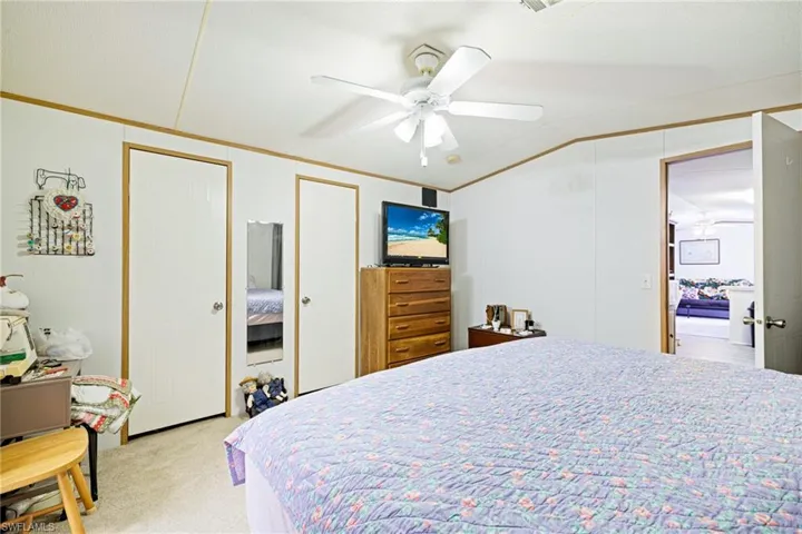 Bedroom with light colored carpet, ornamental molding, two closets, and a ceiling fan