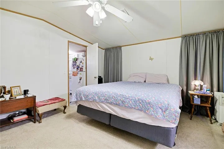 Carpeted bedroom featuring vaulted ceiling and a ceiling fan