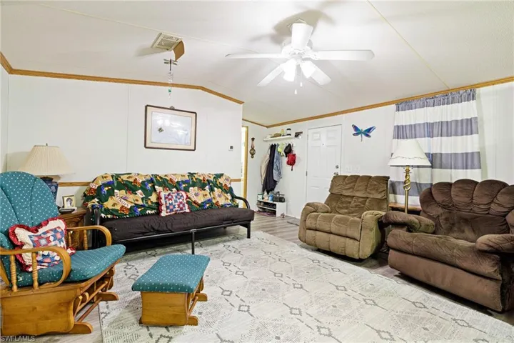Living area featuring crown molding, lofted ceiling, ceiling fan, and new luxury vinyl flooring,