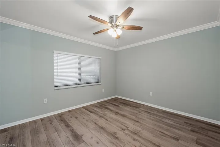 Empty room with ornamental molding, ceiling fan, and wood finished floors