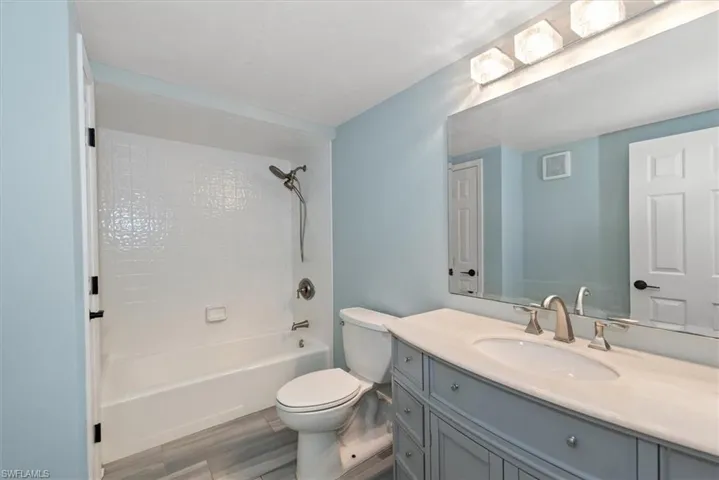 Full bath with vanity, bathing tub / shower combination, and wood finished floors