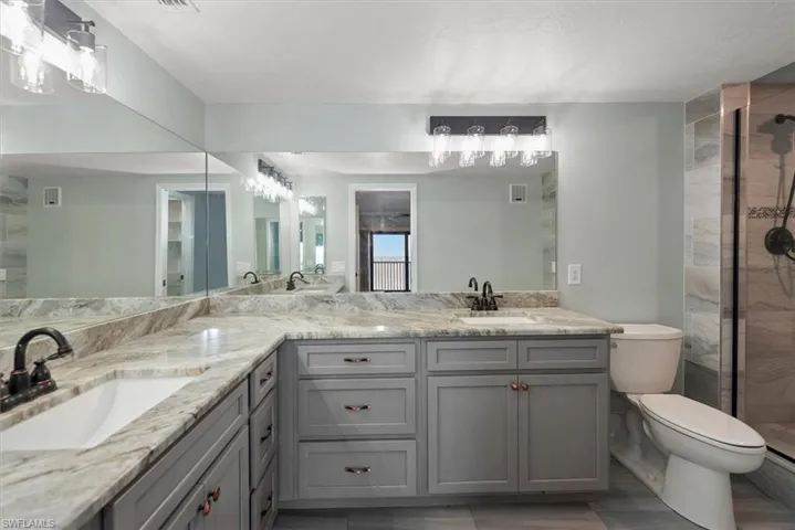 Full bath with double vanity, a stall shower, and wood finished floors