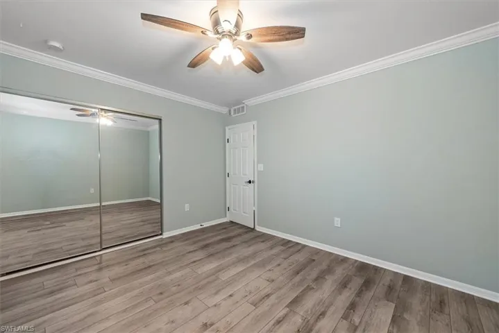 Unfurnished bedroom with wood finished floors, ornamental molding, a closet, and ceiling fan