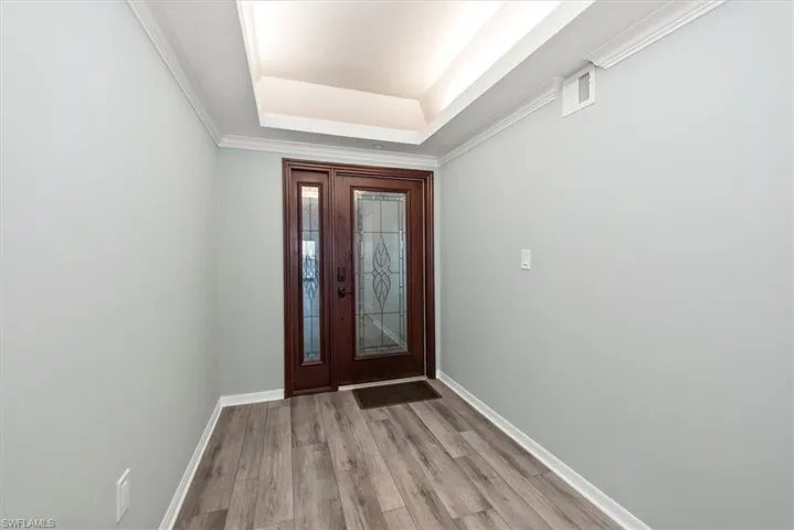 Entrance foyer featuring a raised ceiling and light wood-style floors