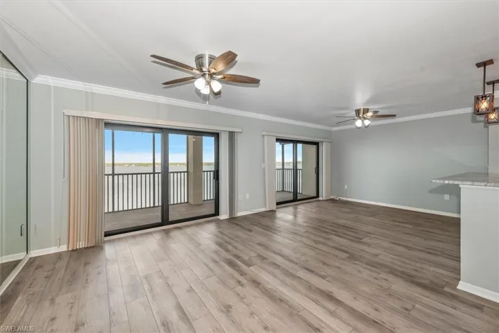 Unfurnished living room featuring a ceiling fan, wood finished floors, and crown molding