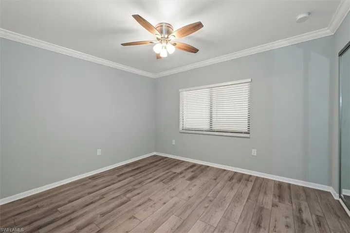 Unfurnished room with ornamental molding, ceiling fan, wood finished floors, and a smoke detector