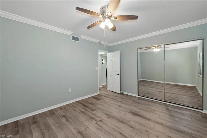 Unfurnished bedroom with ornamental molding, wood finished floors, a closet, and ceiling fan