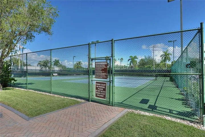 View of tennis court featuring a gate