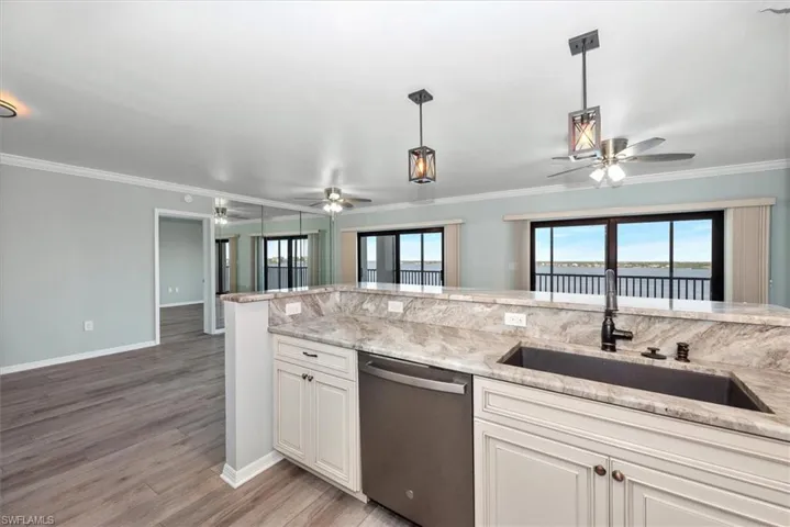 Kitchen with stainless steel dishwasher, a ceiling fan, plenty of natural light, light wood-style floors, and crown molding