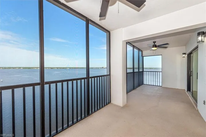 Unfurnished sunroom featuring ceiling fan and a water view