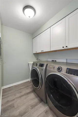 Laundry area with cabinet space, washing machine and dryer, and light wood-style flooring