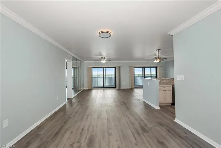 Unfurnished living room with wood finished floors, crown molding, and ceiling fan