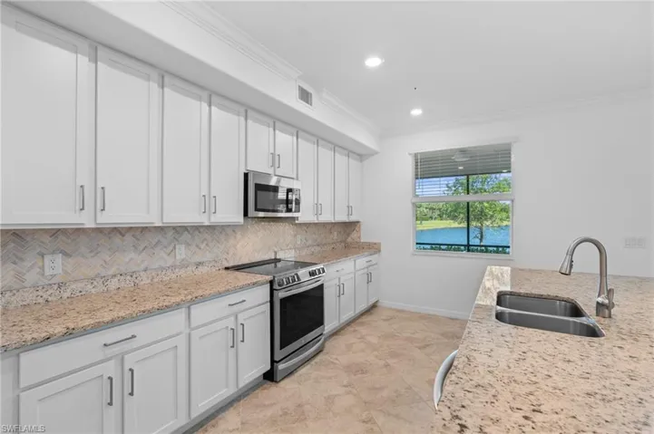 Kitchen with backsplash, a sink, stainless steel appliances, visible vents, and ornamental molding