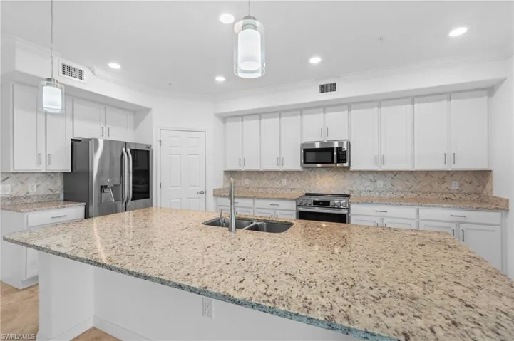 Kitchen featuring visible vents, ornamental molding, a sink, and appliances with stainless steel finishes