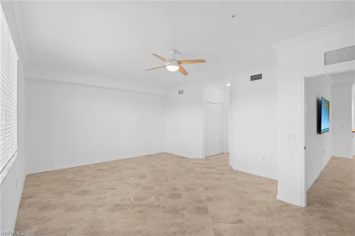 Spare room featuring ornamental molding, baseboards, ceiling fan, and visible vents