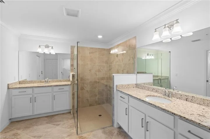 Bathroom with visible vents, ornamental molding, a sink, and a stall shower