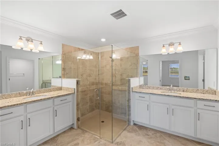 Bathroom with a stall shower, visible vents, crown molding, and a sink