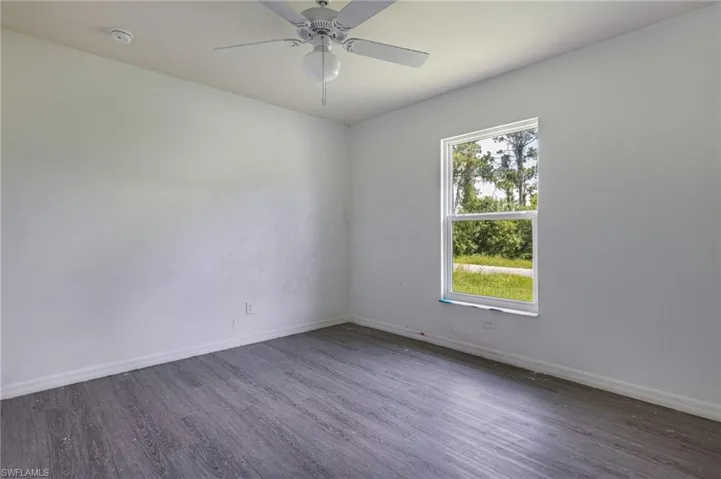 Spare room with ceiling fan, wood-type flooring, and a wealth of natural light