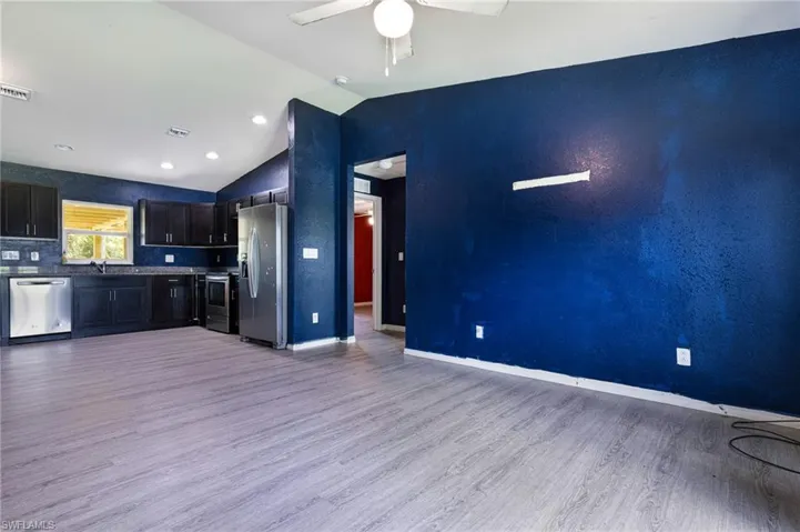 Kitchen with light hardwood / wood-style flooring, lofted ceiling, ceiling fan, appliances with stainless steel finishes, and tasteful backsplash