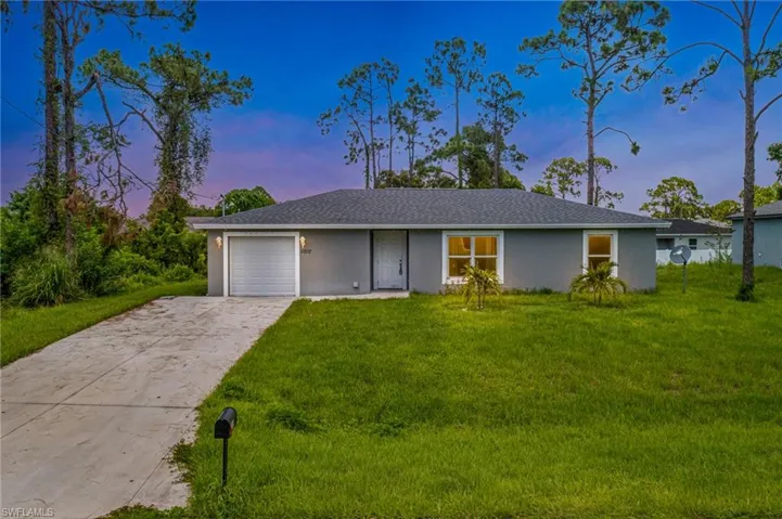 Single story home featuring a garage and a lawn