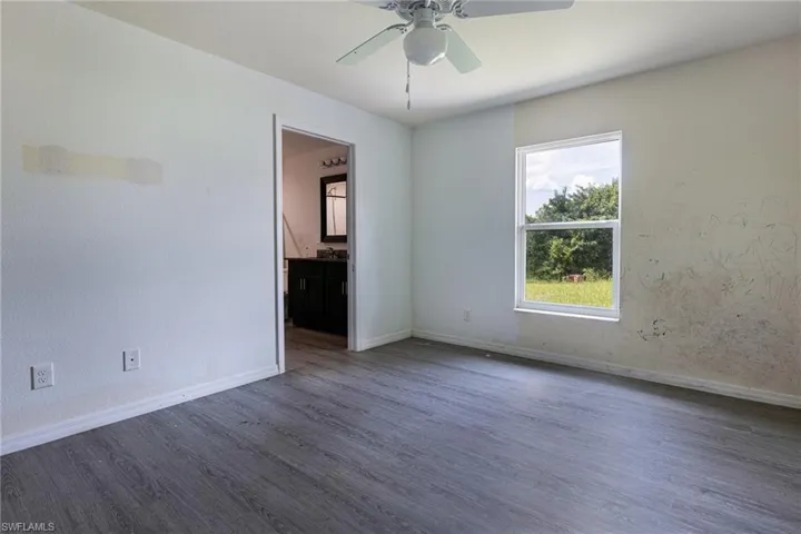 Empty room with ceiling fan and dark hardwood / wood-style flooring