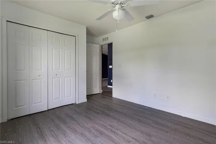 Unfurnished bedroom with ceiling fan, dark hardwood / wood-style flooring, and a closet