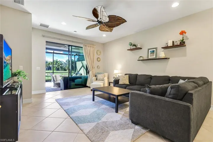 Living room with ceiling fan, light tile patterned floors, and recessed lighting