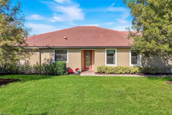 Rear view of property with a lawn, a tile roof, and stucco siding