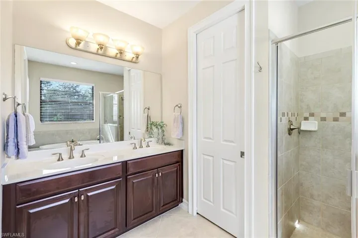 Full bathroom with a shower stall, double vanity, light tile patterned floors, and a garden tub