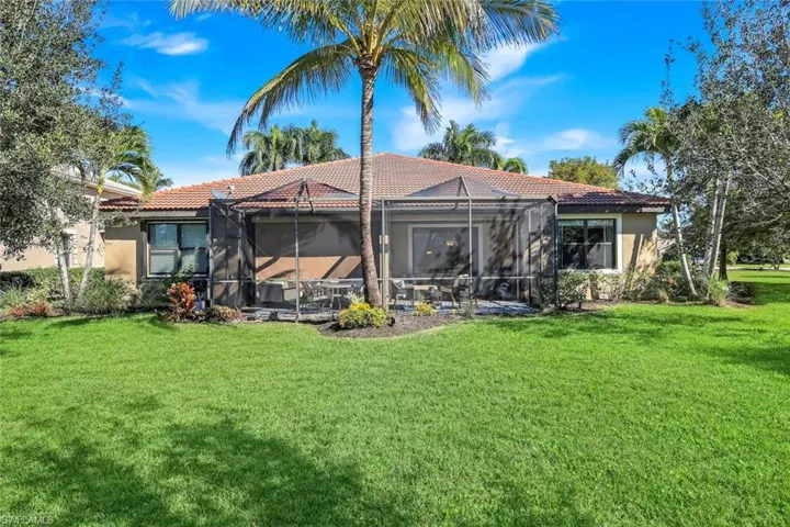 Rear view of property with a lanai, a yard, a tile roof, stucco siding, and a sunroom