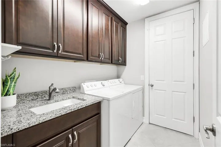 Laundry area with washer and clothes dryer, cabinet space, and light tile patterned floors