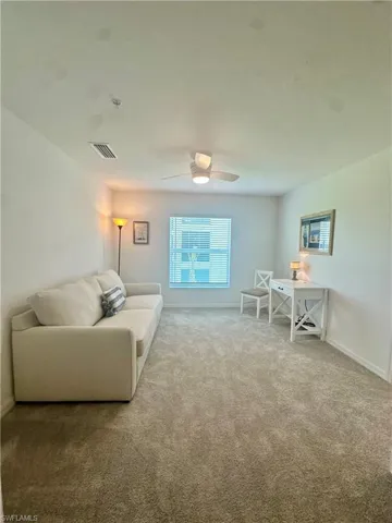 Carpeted living room with baseboards and a ceiling fan