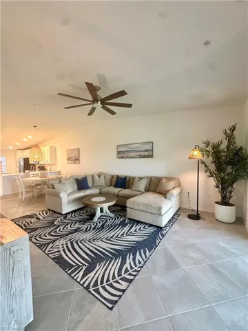 Living area with light tile patterned floors, a ceiling fan, and lofted ceiling