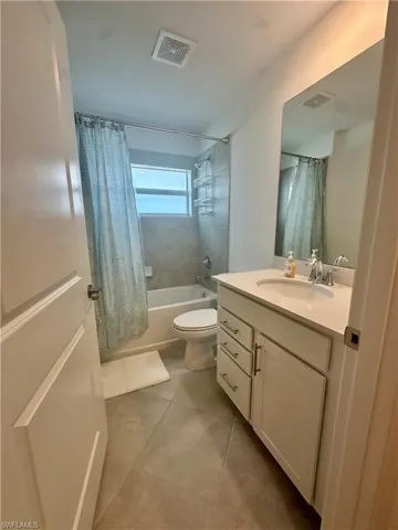 Bathroom featuring shower / bath combo, vanity, tile patterned flooring, and toilet