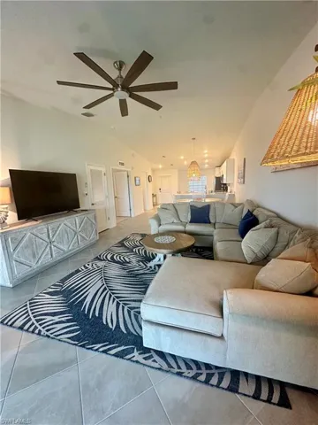Living room with lofted ceiling, ceiling fan, and tile patterned flooring