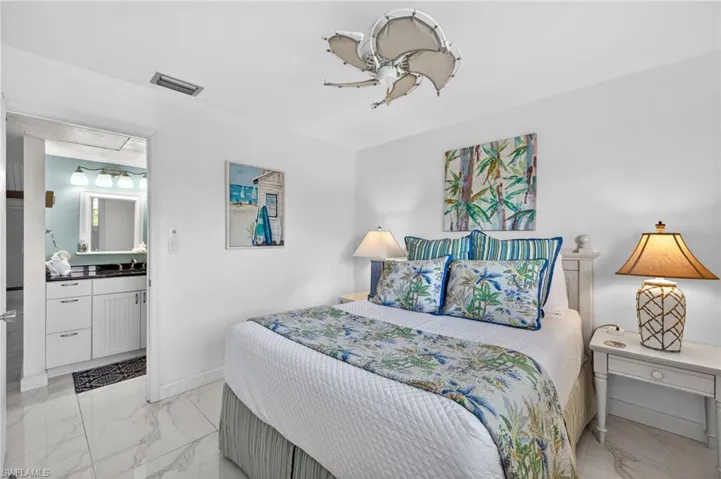 Bedroom featuring white tile flooring, a ceiling fan, and direct access to a bathroom