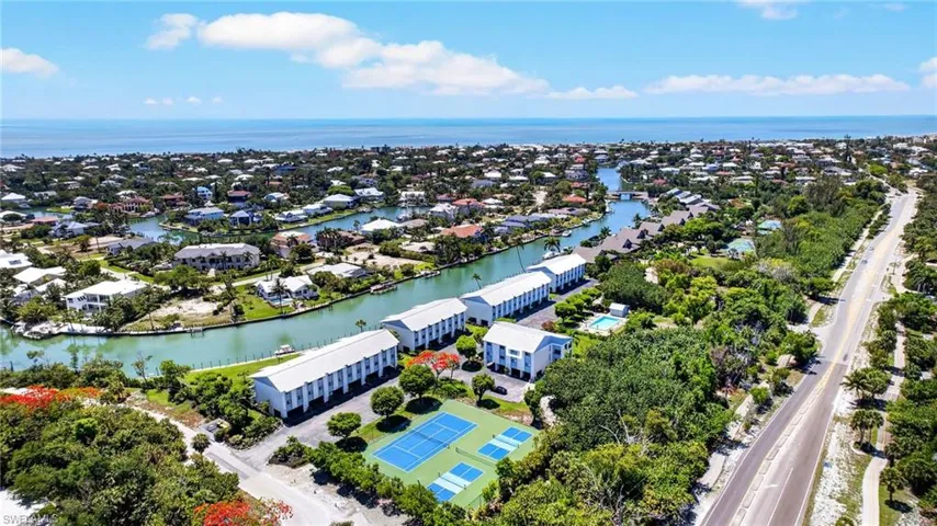 Aerial perspective showcasing coastal properties with canal access, tennis courts, and proximity to the Gulf of Mexico